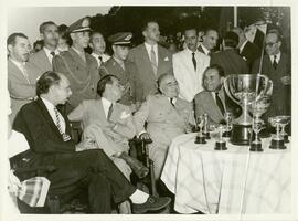 Getúlio Vargas sentado em frente a uma mesa com troféus.
